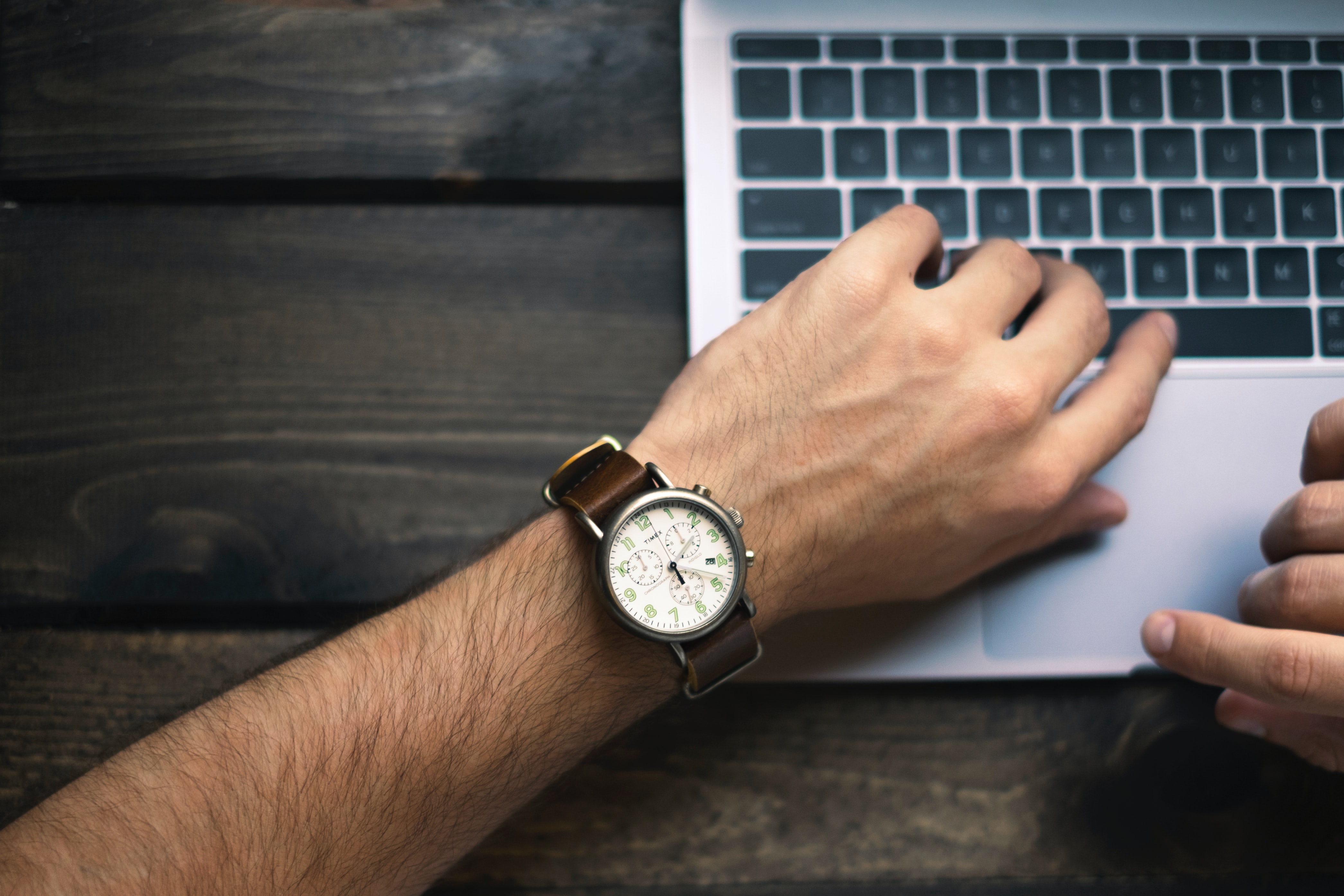 Laptop user looking at watch